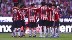 Los jugadores de Chivas reunidos en una parte del campo, mientras platican de lo que va a hacer ese partido