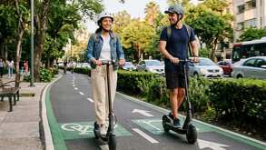 Un hombre y una mujer conduciendo patines eléctricos sobre una ciclovía