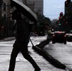 Un hombre cruza la calle mientras usa un paraguas para protegerse de la lluvia.