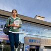 Estudiante con una libreta en las manos y detrás el edificio principal UNITEC en Puebla