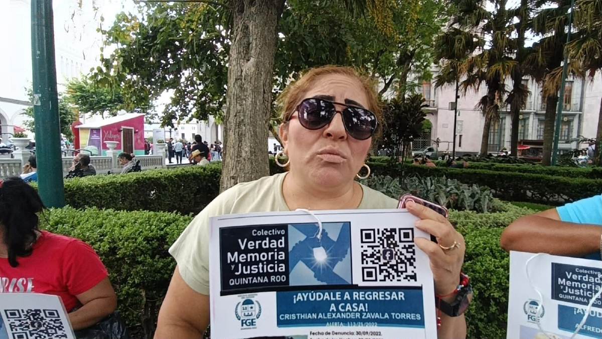 una mujer sostiene un cartel de búsqueda de su hijo desaparecido