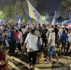 Se observa a varias personas de pie reunidas en un espacio público.