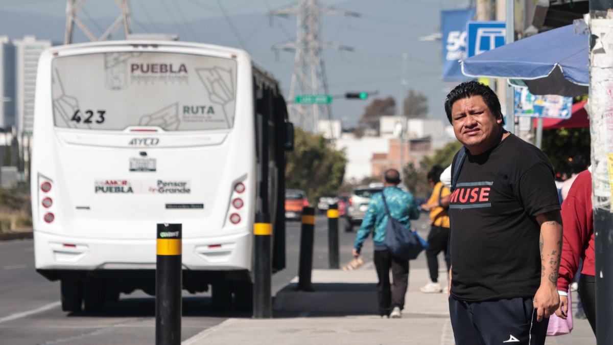 Hombre esperando el transporte público en una calle de Puebla.