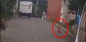 un bebé en una calle por donde pasan vehículos