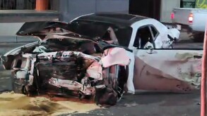 Automóvil color blanco con la puerta del conductor abierta y completamente destruido de la parte de enfrente tras un aparatoso choque