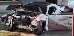 Automóvil color blanco con la puerta del conductor abierta y completamente destruido de la parte de enfrente tras un aparatoso choque