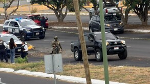 Policías del Estado de Colima, militares del ejército y grupo de personas en un área acordonada con una camioneta negra donde un hombre fue asesinado a balazos