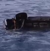 Camioneta pickup color gris volcada dentro del mar mientras es arrastrada por el fuerte oleaje provocado por el mar de fondo