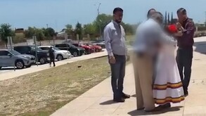 Se observa a varios hombres rodeando a una niña vestida de blanco.