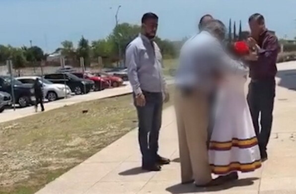 Se observa a varios hombres rodeando a una niña vestida de blanco.