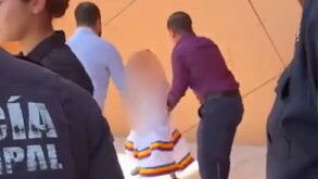 Se observa a dos hombres de pie y una niña que trae un vestido blanco.