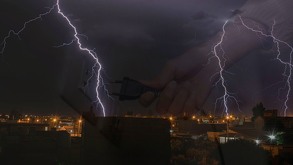 Imagen de tormenta eléctrica en primer plano y de fondo la imagen tenues de una mano desenchufando el electrodoméstico