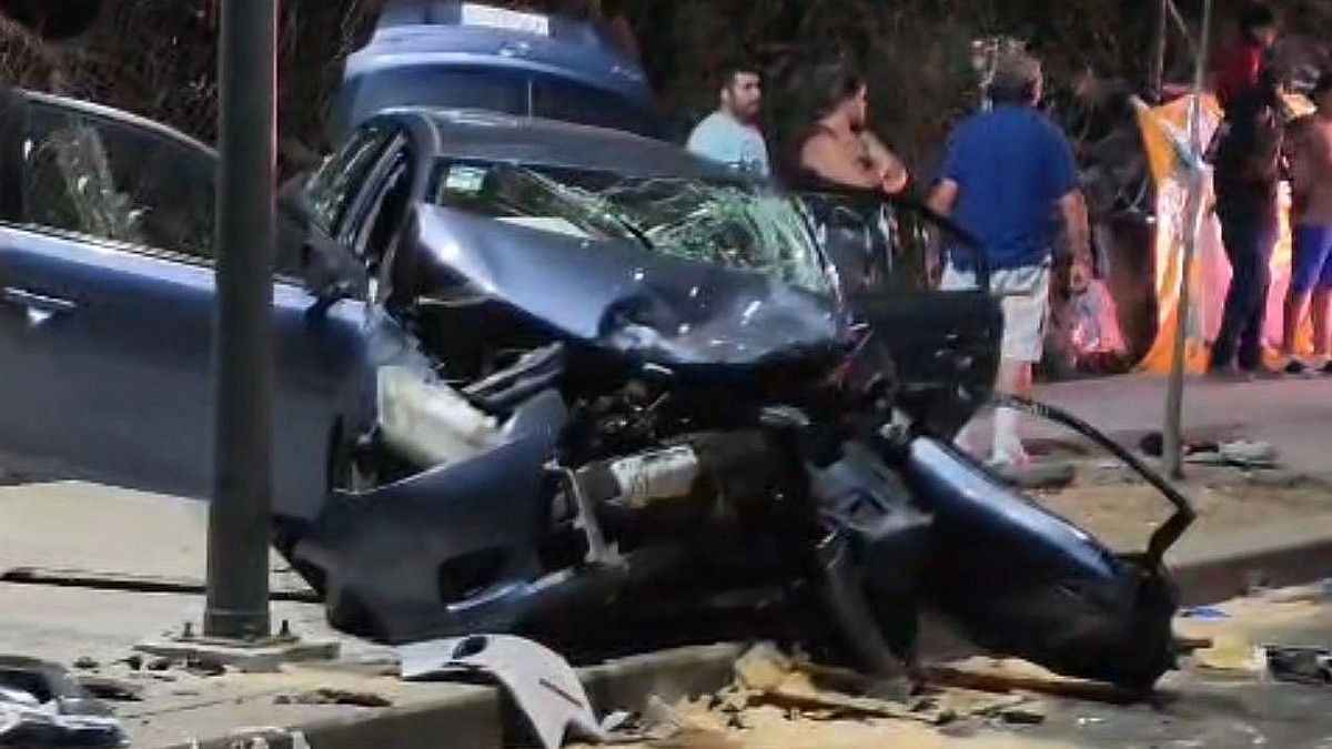 Automóvil color azul con las puertas y la cajuela abiertas y la parte de enfrente completamente destrozada tras un choque múltiple