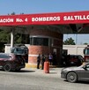 Se observa una fachada de un establecimiento en color gris con rojo y tiene letras que dice Estación de Bomberos.