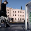 Se ve a un hombre caminando, usa lentes de sol y lleva con una correa a un perro dalmata.