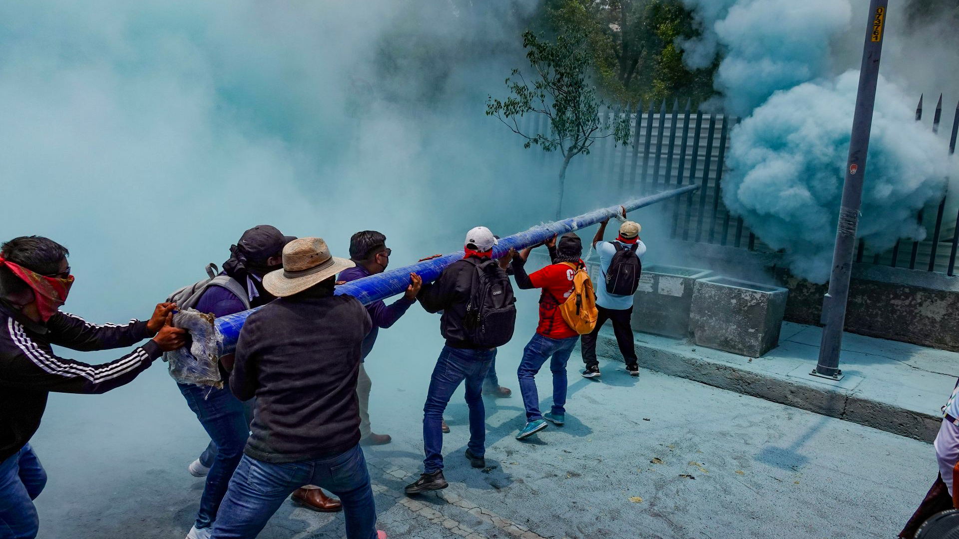 Grupos de la CNTE con el rostro cubierto usaron postes de luminarias para destrozar los accesos de las Oficinas de Educación Primaria de la SEP.