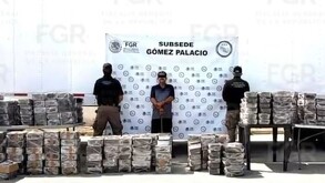 Hombre esposado y con los ojos censurados por un recuadro negro en medio de dos agentes de la FGR delante de varios paquetes de metanfetamina