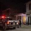 Se observa una patrulla, una mujer policía y otras personas de pie; es de noche.
