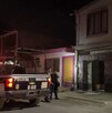 Se observa una patrulla, una mujer policía y otras personas de pie; es de noche.