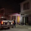 Se observa una patrulla, una mujer policía y otras personas de pie; es de noche.