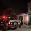 Se observa una patrulla, una mujer policía y otras personas de pie; es de noche.