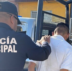 Se observa a un policía sometiendo a un hombre que está de espaldas.