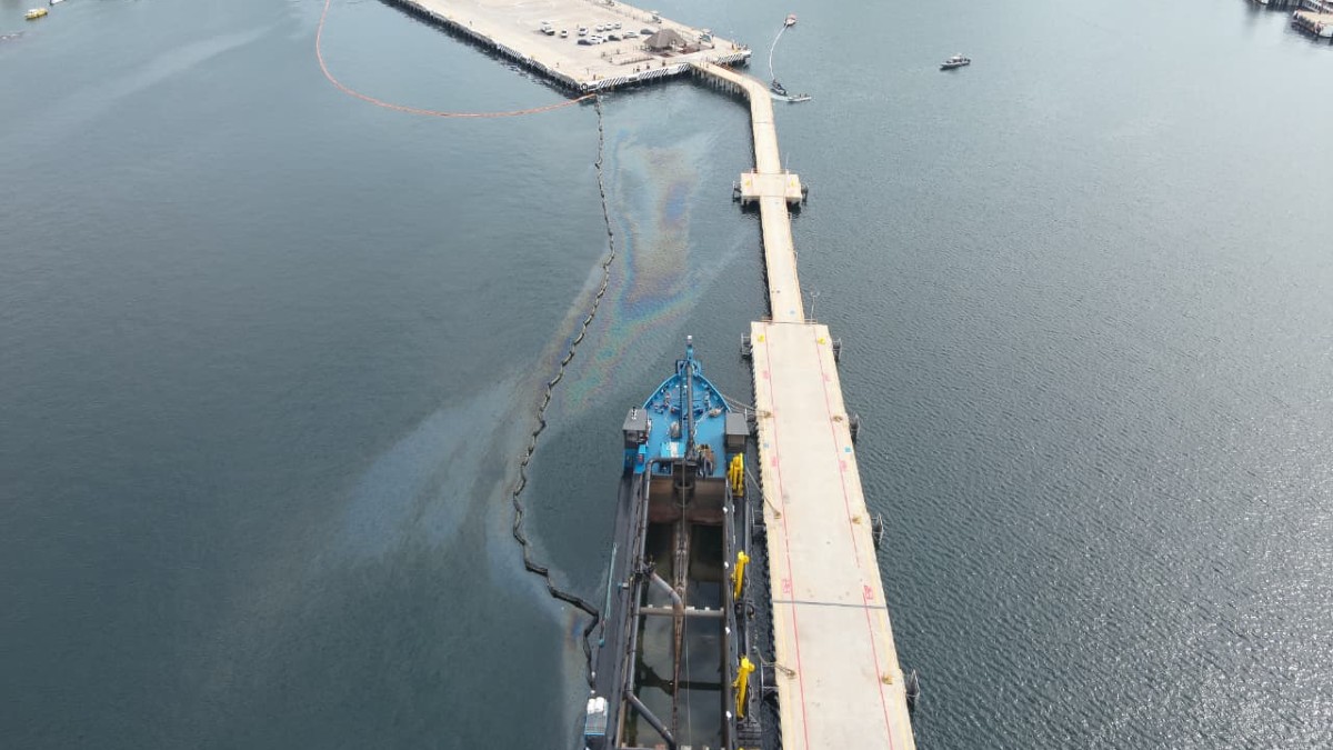 Vista cenital de una mancha de hidrocarburo aceitosa en el puerto de Manzanillo, Colima con un barco resguardando el sitio