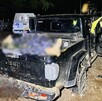 Vista de la caja de una camioneta Jeep color negro con las puertas abiertas y una persona con rastros de sangre censurados con blur