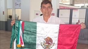Braulio sostiene la bandera de México en el aeropuerto con maletas