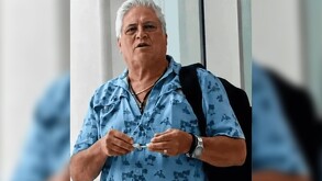 Empresario joyero de Jalisco Jaime Arias García vistiendo una camisa azul y una mochila negra al hombro delante de unas cortinas blancas