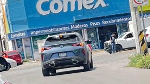 Se observa un carro sobre la calle y al fondo un letrero.