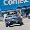 Se observa un carro sobre la calle y al fondo un letrero.