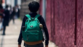 Niño con una mochila caminando hacia una escuela.