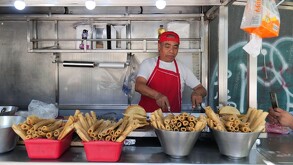 Hombre prepara comida en un puesto callejero en CdMx