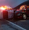 Se observa un tractocamión siniestrado y una camioneta destrozada tras un choque; es de noche.