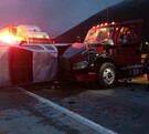 Se observa un tractocamión siniestrado y una camioneta destrozada tras un choque; es de noche.