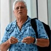 Empresario joyero de Jalisco Jaime Arias García vistiendo una camisa azul y una mochila negra al hombro delante de unas cortinas blancas