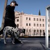 Se ve a un hombre caminando, usa lentes de sol y lleva con una correa a un perro dalmata.