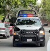 Se observa una patrulla en medio de la calle y hay vehículos estacionados a los costados.