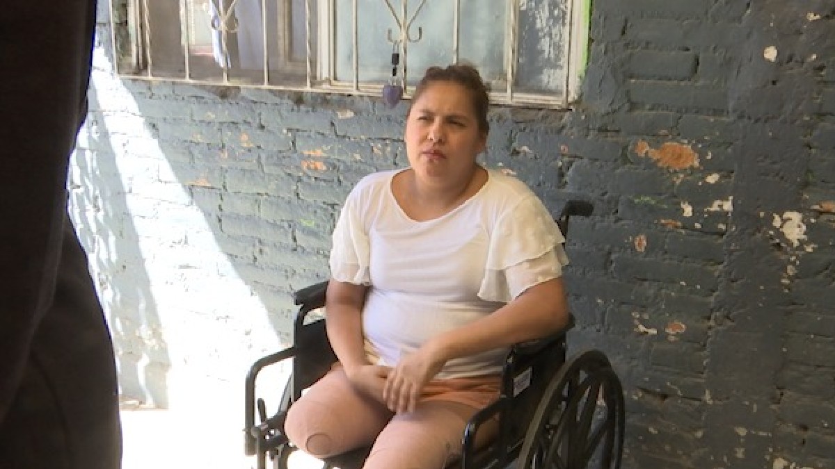 Mujer con playera gris y en una silla de ruedas