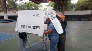 Se observa a un hombre dentro de una casilla electoral.