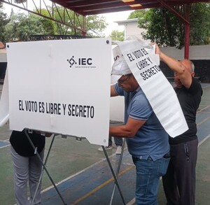 Se observa a un hombre dentro de una casilla electoral.
