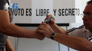 Foto en primer plano de un pulgar siendo pintado con la tinta que representa el voto ejercido en un proceso electoral