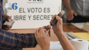 Imagen en primer plano de una persona con camisa de rayas poniendo su pulgar para la colocación de la tinta tras emitir su voto.