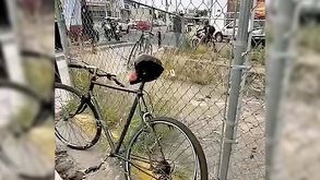 Bicicleta apoyada en una reja con ciclistas y automóviles circulando en calles de Zapopan