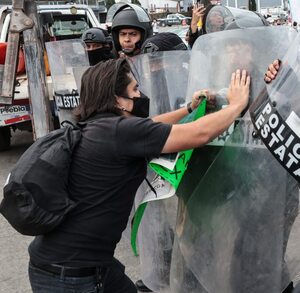 Manifestante peleando con un policía en Puebla.