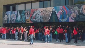 Se observa a varias personas que visten playera roja y están de pie.
