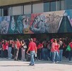 Se observa a varias personas que visten playera roja y están de pie.