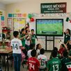 Foto de niños en un aula de clases viendo el mundial con maestros.