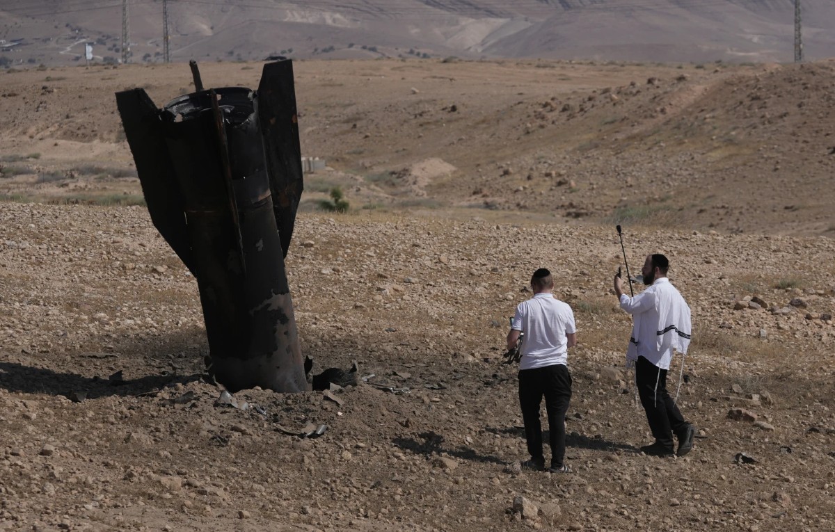Gente inspecciona los restos de un misil iraní que cayó cercad de la ciudad de cisjordania de Jerico